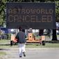 A pedestrian cross Main Street in front of a sign announcing the cancellation of Astroworld on Saturday, Nov. 6, 2021, in Houston.  Several people died and numerous others were injured in what officials described as a surge of the crowd at the music festival while Travis Scott was performing Friday night.  (AP Photo/Michael Wyke)