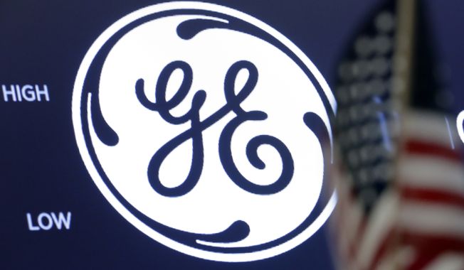 The General Electric logo appears above a trading post on the floor of the New York Stock Exchange, June 26, 2018. General Electric is splitting itself into three public companies that concentrate on aviation, health care and energy. The company said Tuesday, Nov. 9, 2021, that it plans a spinoff of its health hcare business in early 2023 and of its energy segment in early 2024. (AP Photo/Richard Drew, File)