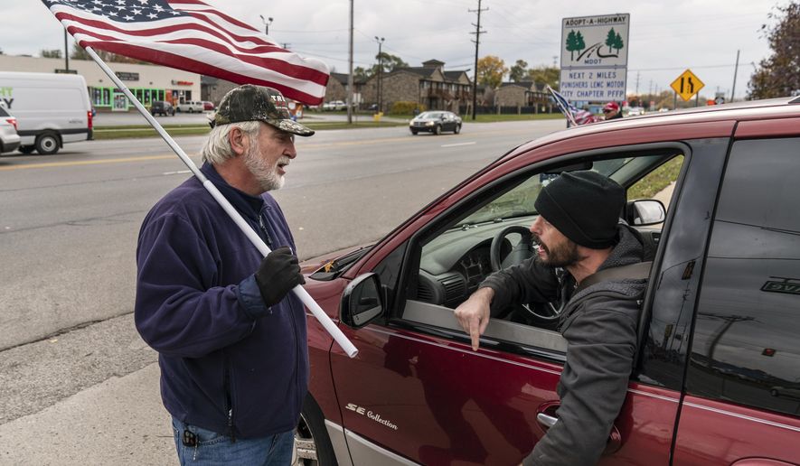 A passing motorist argues with Trump supporter Mike Jamerson, left, during a rally at an intersection in Mount Clemens, Michigan, on Oct. 29, 2020. Americans are exhausted from constant crises, on edge because of volatile political divisions and anxious about what will happen next. (AP Photo/David Goldman)