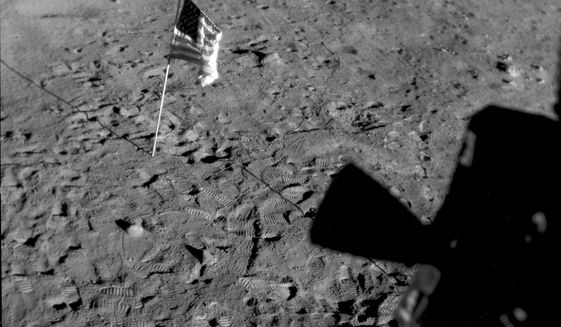 This July 21, 1969, photo made available by NASA shows a U.S. flag planted at Tranquility Base on the surface of the moon, and a silhouette of a thruster at right, seen from a window in the Lunar Module. On Tuesday, Nov. 9, 2021, NASA announced it is delaying putting astronauts back on the moon until 2025 at the earliest. (NASA via AP, File)