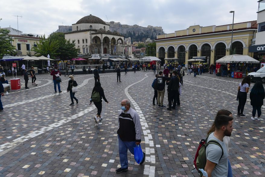 Pedestrians, some of them wearing face masks to protect against coronavirus, walk at Monastiraki square, Athens, Greece, Tuesday, Nov. 9, 2021. Greece reported a new record high for daily COVID-19 infections on Monday as vaccination appointments shot up after new restrictions on unvaccinated people kicked in over the weekend. (AP Photo/Michael Varaklas)