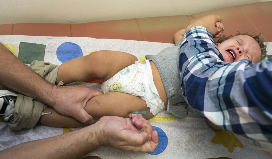 In this Jan. 29, 2015, photo, pediatrician Charles Goodman vaccinates 1-year-old Cameron Fierro with the measles-mumps-rubella vaccine, or MMR vaccine, at his practice in Northridge, Calif. (AP Photo/Damian Dovarganes) **FILE**