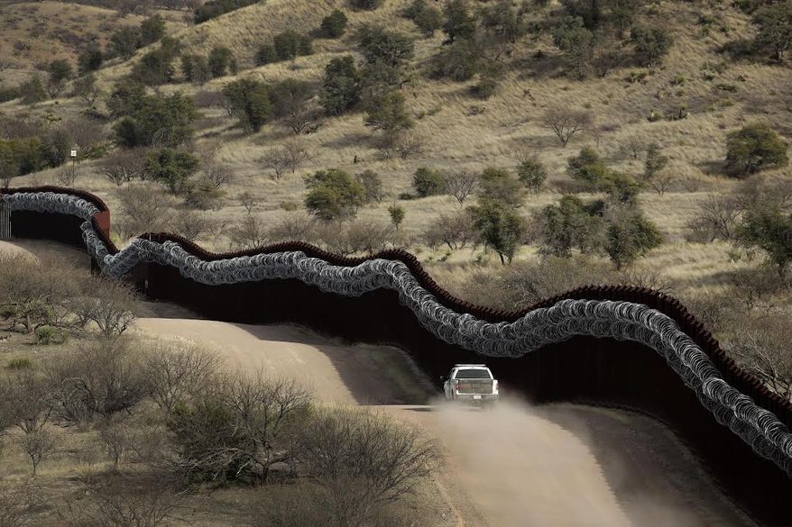 In this March 2, 2019, file photo, a Customs and Border Control agent patrols on the U.S. side of a razor-wire-covered border wall along Mexico east of Nogales, Ariz. (AP Photo/Charlie Riedel, File)