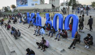 FILE - People sit on steps next to a sculpture in the shape of Amharic words reading &quot;Addis Ababa&quot; in the Piazza old town area of the capital Addis Ababa, Ethiopia Thursday, Nov. 4, 2021. American and British citizens have been swept up in Ethiopia&#39;s mass detentions of ethnic Tigrayans under a new state of emergency in the country&#39;s escalating war. Thousands of Tigrayans have already been detained and fears of more such detentions soared on Thursday, Nov. 11 as Ethiopian authorities ordered landlords to register the identities of their tenants with police. (AP Photo, File)