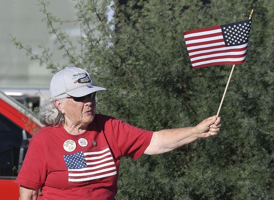A woman waves a small American flag as a U.S. Marine Corps Color Guard marches past near the start of the 2021 Veterans Day Parade, presented by H.H. Donkersley American Legion Post 19, Thursday, Nov. 11, 2021, in Yuma, Ariz. (Randy Hoeft/The Yuma Sun via AP) ** FILE **