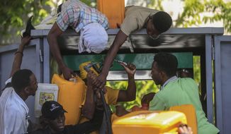 People wrangle over a gas pump as they try to get their tanks filled at a gas station, in Port-au-Prince, Haiti, Thursday. Nov 4, 2021. (AP Photo/Odelyn Joseph)