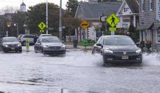 This Oct. 11, 2019, photo shows cars kicking up spray while driving through a flooded street in Bay Head, N.J. Bay Head is studying options to prevent, or at least reduce, incidents of so-called “sunny day” flooding caused by tides and rising sea levels, as well as major storm-related floods. New Jersey&#39;s Department of Environmental Protection and the U.S. Army Corps of Engineers have proposed a massive $16 billion plan to address back bay flooding along the shore. (AP Photo/Wayne Parry)