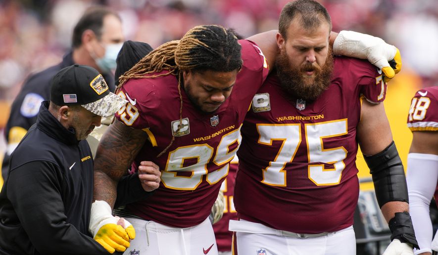 Washington Football Team defensive end Chase Young (99) is helped off the field by guard Brandon Scherff (75) after an injury during the first half of an NFL football game against the Tampa Bay Buccaneers, Sunday, Nov. 14, 2021, in Landover, Md. (AP Photo/Nick Wass)
