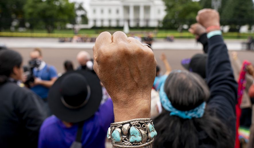 FILE - Wolf Ramerez of Houston, Texas, center, joins others with the Carrizo Comecrudo Tribe of Texas in holding up his fists as indigenous and environmental activists protest in front of the White House in Washington, Oct. 11, 2021. President Joe Biden will announce steps Monday, Nov. 15, to improve public safety and justice for Native Americans during the first tribal nations summit since 2016, the White House said. (AP Photo/Andrew Harnik, File)