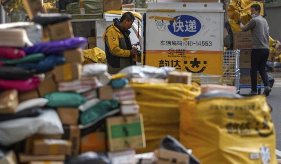 Workers of a private delivery company sort out parcels piled up at a pickup point near a residential apartment buildings in Beijing, Tuesday, Nov. 16, 2021. Chinese data reported Monday showed October retail sales growth weakened compared with the previous month, weakened by anti-coronavirus restrictions and consumer unease over a wave of outbreaks. (AP Photo/Andy Wong)