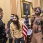 Supporters of President Donald Trump, including Jacob Chansley, right with fur hat, are confronted by U.S. Capitol Police officers outside the Senate chamber inside the Capitol during the capitol riot in Washington, Jan. 6, 2021. Chansley was sentenced on Wednesday, Nov. 17, 2021, to 41 months in prison for his felony conviction for obstructing an official proceeding. Though he wasn&#x27;t accused of violence, Chansley acknowledged he was among the first 30 rioters in the building, offered thanks while in the Senate for having the chance to get rid of traitors and wrote a threatening note to Vice President Mike Pence. (AP Photo/Manuel Balce Ceneta, File)