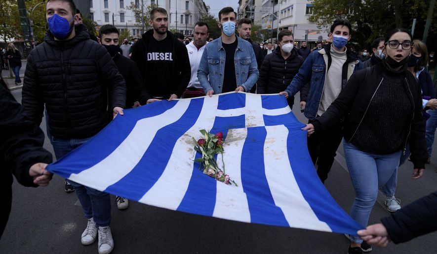 University students hold a blood-stained Greek flag from the deadly 1973 student uprising during a rally in Athens, on Wednesday, Nov. 17, 2021. More than 5,000 police officers are being deployed in Athens ahead of a rally to mark the 47th anniversary of a bloody anti-dictatorship uprising. The large student-led demonstrations in 1973 at the Athens Polytechnic in the center of the capital were held a year before a military dictatorship, in power since 1967, collapsed. (AP Photo/Thanassis Stavrakis)