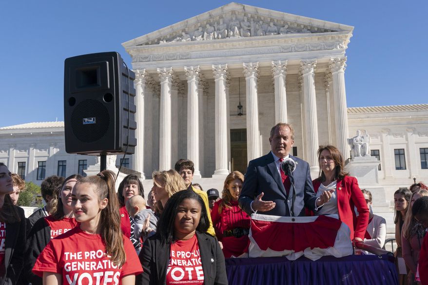 Texas Attorney General Ken Paxton addresses anti-abortion activists at a rally outside the Supreme Court, Monday, Nov. 1, 2021, on Capitol Hill in Washington, after hearing arguments on abortion in the court, as his wife and Texas State Sen. Angela Paxton, stands right.  (AP Photo/Jacquelyn Martin)