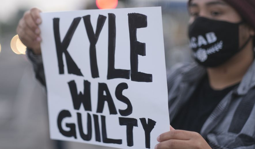 A protester holds up a sign, Friday, Nov. 19, 2021, in Los Angeles, following the acquittal of Kyle Rittenhouse in Kenosha, Wis. Asserting self-defense, Rittenhouse was acquitted of all charges Friday in the deadly Kenosha shootings that became a flashpoint in the debate over guns, vigilantism and racial injustice in the U.S. (AP Photo/Ringo H.W. Chiu)