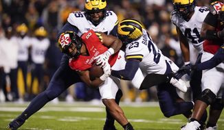 Maryland running back Tayon Fleet-Davis (8) is tackled by Michigan defensive lineman Donovan Jeter (95) and linebacker Michael Barrett (23) during the first half of an NCAA college football game, Saturday, Nov. 20, 2021, in College Park, Md. Michigan won 59-18. (AP Photo/Julio Cortez)