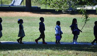 Elementary school students walk back to class following their lunch period at Glenmount Elementary/Middle School, Nov. 1, 2021, in northeast Baltimore, Md. Eight weeks into the school year in Northeast Baltimore’s Glenham-Belhar neighborhood, the school’s teachers are relieved to be back. (Jerry Jackson/The Baltimore Sun via AP)
