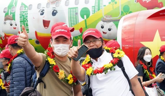 Tourists pose for a photo after landing on Phu Quoc island, in Vietnam, Saturday, Nov. 20, 2020. More than 200 foreign tourists arrived on Vietnam&#39;s largest Phu Quoc island on Saturday, being the first to visit the Southeast Asian country after nearly two years of border closure due to COVID-19. (VietjetAir via AP)