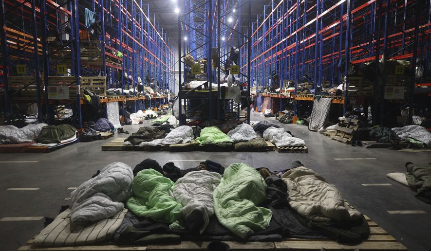 Migrants sleep a logistics center at the checkpoint &quot;Kuznitsa&quot; at the Belarus-Poland border near Grodno, Belarus, Monday, Nov. 22, 2021. Belarus President Alexander Lukashenko on Monday chafed at the European Union for its refusal to hold talks on the influx of migrants on the country&#39;s border with Poland and urged Germany to accommodate about 2,000 migrants who had remained on the border with Poland. (Maxim Guchek/BelTA via AP)