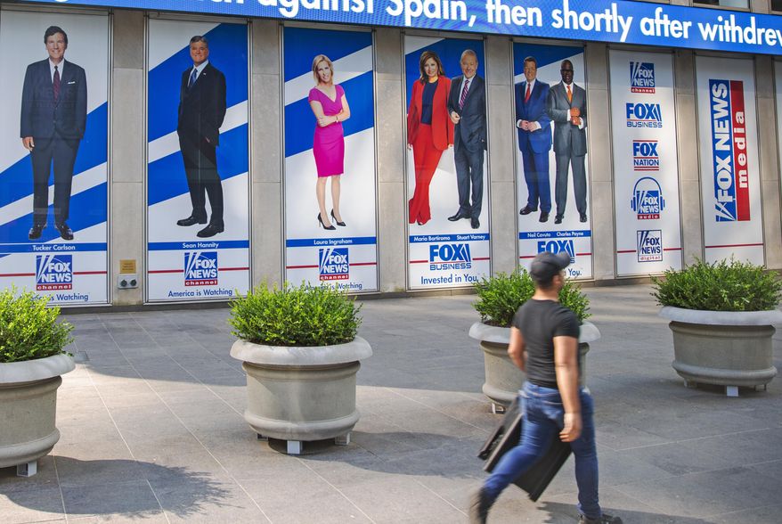 Images of Fox News personalities, from left, Tucker Carlson, Sean Hannity, Laura Ingraham, Maria Bartiromo, Stuart Varney, Neil Cavuto and Charles Payne appear outside News Corporation headquarters in New York on July 31, 2021. (AP Photo/Ted Shaffrey, File)