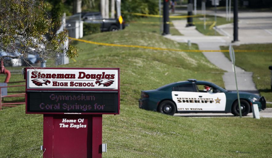 Law enforcement officers block off the entrance to Marjory Stoneman Douglas High School on Feb. 15, 2018 in Parkland, Fla., following a deadly shooting at the school. The families of most of those killed in the 2018 Florida high school massacre have settled their lawsuit against the federal government. Sixteen of the 17 killed at Marjory Stoneman Douglas High in Parkland had sued over the FBI’s failure to stop the gunman even though it had received information he intended to attack. The settlement reached Monday, Nov. 22, 2021, is confidential. (AP Photo/Wilfredo Lee, File)