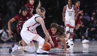 In this photo provided by Bahamas Visual Services, South Carolina forward Victaria Saxton (5), right, guard Destanni Henderson (3), left, and UConn guard Paige Bueckers (5), foreground, fight for ball possession during an NCAA college basketball game at Paradise Island, Bahamas, Monday, Nov. 22, 2021. (Tim Aylen/Bahamas Visual Services via AP)