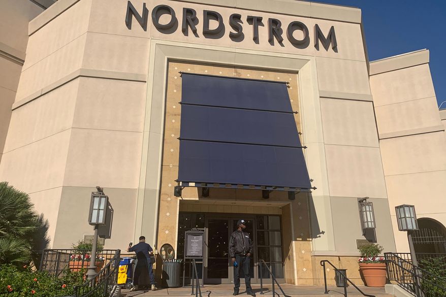 A security guard stands outside the Nordstrom store at The Grove retail and entertainment complex in Los Angeles, Tuesday, Nov. 23, 2021. Los Angeles police say a group of thieves smashed windows at the department store at the luxury mall late Monday, the latest incident in a trend of smash-and-grab crimes is part of a national trend. (AP Photo/Eugene Garcia)
