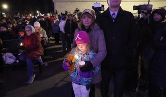 A small child takes part in a candle light vigil in downtown Waukesha, Wis., Monday, Nov. 22, 2021 after an SUV plowed into a Sunday Christmas parade killing multiple people and injuring dozens. (AP Photo/Jeffrey Phelps)