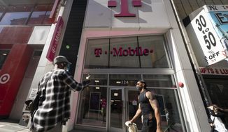 A man uses a mobile phone outside a T-Mobile store, Monday, April 19, 2021,  in New York. The wireless carrier agreed to pay $19.5 million in a settlement with the Federal Communications Commission over a 12-hour nationwide outage in June 2020 that resulted in thousands of failed 911 calls. The FCC said Tuesday, Nov. 23 that as part of the settlement, T-Mobile will also commit to improving communications of outages to emergency call centers, among other measures. (AP Photo/Mark Lennihan)