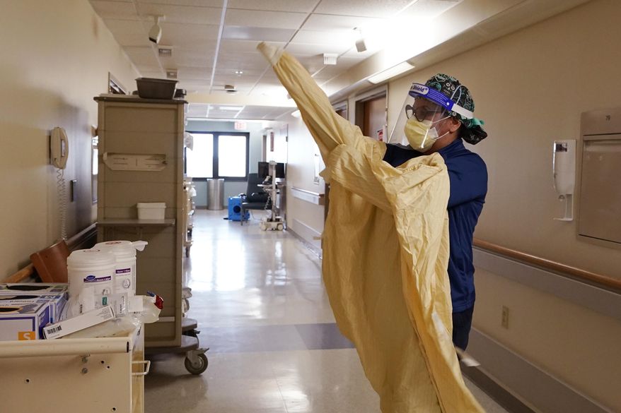 FILE - Registered Nurse Monica Quintana dons protective gear before entering a room at the William Beaumont hospital, April 21, 2021 in Royal Oak, Mich. The federal government will send 44 military medical personnel to Michigan to help beleaguered hospitals treat COVID-19 patients amid a fourth surge that is the worst in the country, state health officials said Wednesday, Nov. 24. (AP Photo/Carlos Osorio, file)