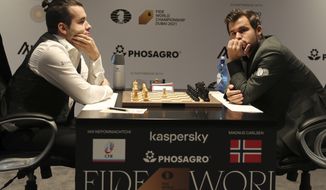 Norway&#39;s World Chess Champion Magnus Carlsen, right, and Ian Nepomniachtchi of Russia, compete during their Game One of the FIDE World Championship at the Dubai Expo, in Dubai, United Arab Emirates, Friday, Nov. 26, 2021. (AP Photo/Kamran Jebreili)
