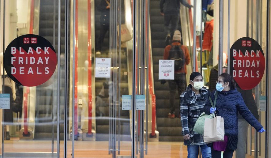 FILE - Black Friday shoppers wear face masks and gloves during the coronavirus pandemic as they leave the Uniqlo store along Fifth Avenue, Friday, Nov. 27, 2020, in New York. Retailers are expected to usher in the unofficial start to the holiday shopping season Friday, Nov. 26, 2021, with bigger crowds than last year in a closer step toward normalcy. But the fallout from the pandemic continues to weigh on businesses and shoppers&#39; minds. (AP Photo/Mary Altaffer, File)