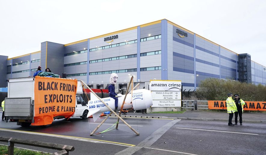 Activists from Extinction Rebellion block the entrance to the Amazon fulfilment centre, preventing lorries from entering or leaving on Black Friday, the global retail giant&#39;s busiest day of the year, in Tilbury, England,  Friday Nov. 26, 2021. The group has targeted Amazon sites in Doncaster, Darlington, Dunfremline, Newcastle, Manchester, Peterborough, Derby, Coventry, Rugeley, Dartford, Bristol, Tilbury and Milton Keynes. (Ian West/PA via AP)