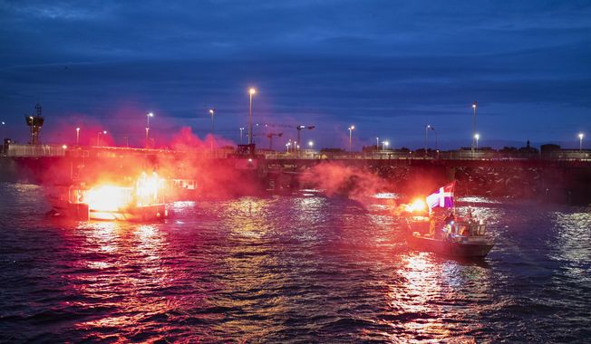 French fishermen light flares as they block the entrance to the port of Saint-Malo, western France, Friday, Nov. 26, 2021. French fishing crews are threatening to block French ports and traffic under the English Channel on Friday to disrupt the flow of goods to the U.K., in a dispute over post-Brexit fishing licenses. (AP Photo/Jeremias Gonzalez)