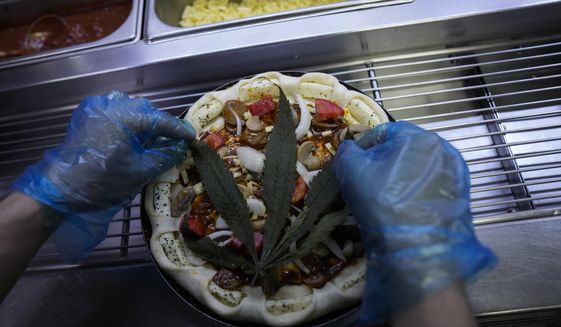 A cannabis leaf is put on a pizza at a restaurant in Bangkok, Thailand on Nov. 24, 2021. The Pizza Company, a Thai major fast food chain, has been promoting its &amp;quot;Crazy Happy Pizza&amp;quot; this month, an under-the-radar product topped with a cannabis leaf. It’s legal but won’t get you high.  (AP Photo/Sakchai Lalit)