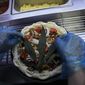 A cannabis leaf is put on a pizza at a restaurant in Bangkok, Thailand on Nov. 24, 2021. The Pizza Company, a Thai major fast food chain, has been promoting its &amp;quot;Crazy Happy Pizza&amp;quot; this month, an under-the-radar product topped with a cannabis leaf. It’s legal but won’t get you high.  (AP Photo/Sakchai Lalit)