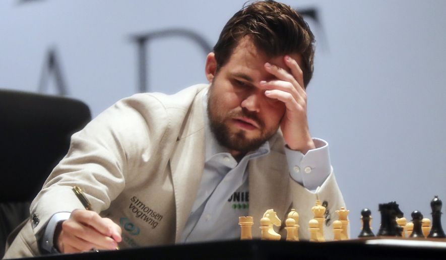 Norway&#39;s World Chess Champion Magnus Carlsen, takes a note during their game two against Ian Nepomniachtchi of Russia, of the FIDE World Championship at the Dubai Expo, in Dubai, United Arab Emirates, Saturday, Nov. 27, 2021. (AP Photo/Kamran Jebreili)