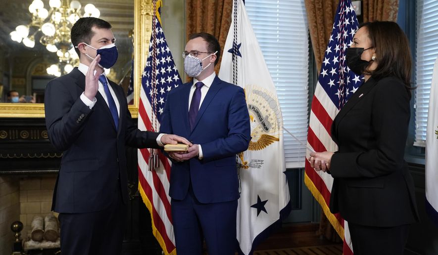 Pete Buttigieg, with his hand on a Bible held by husband Chasten Buttigieg, is sworn in as Transportation Secretary by Vice President Kamala Harris in the Old Executive Office Building in the White House complex on Feb. 3, 2021. (AP Photo/Andrew Harnik) ** FILE **