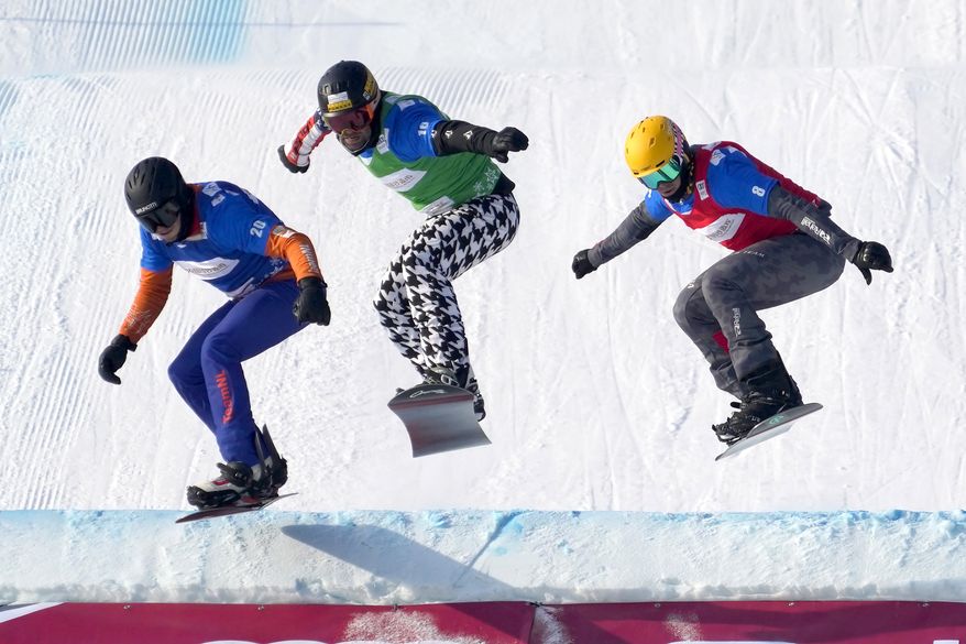From left, Glenn de Blois of the Netherlands, Nick Baumgartner of the United States, and Jakob Dusek of Austria compete during a semifinal of men&#39;s snowboard cross at the FIS Snowboard Cross World Cup, a test event for the 2022 Winter Olympics, at the Genting Resort Secret Garden in Zhangjiakou in northern China&#39;s Hebei Province, Sunday, Nov. 28, 2021. (AP Photo/Mark Schiefelbein)