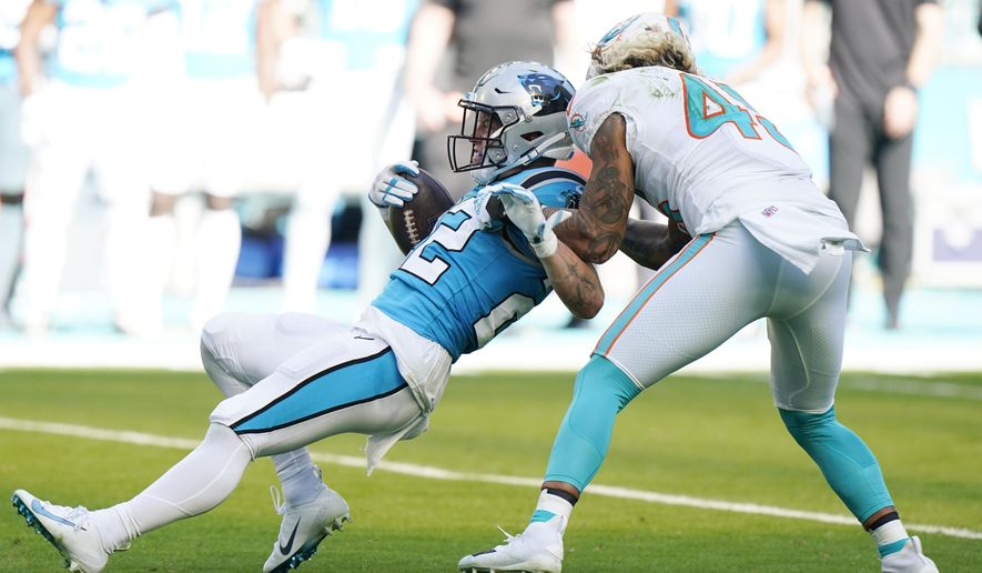 Miami Dolphins outside linebacker Duke Riley (45) grabs Carolina Panthers running back Christian McCaffrey (22) during the first half of an NFL football game, Sunday, Nov. 28, 2021, in Miami Gardens, Fla. (AP Photo/Wilfredo Lee) **FILE**