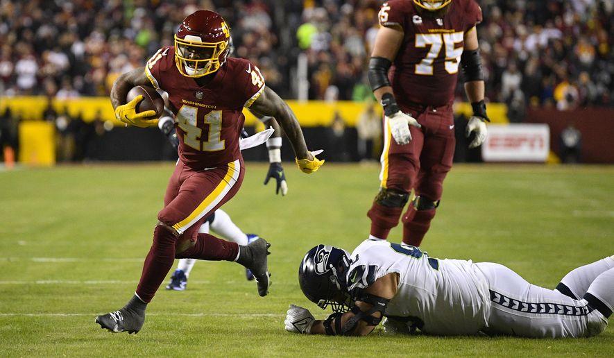 Washington Football Team running back J.D. McKissic (41) break away from Seattle Seahawks defensive tackle Bryan Mone (90) to score a touchdown during the first half of an NFL football game, Monday, Nov. 29, 2021, in Landover, Md. (AP Photo/Nick Wass)