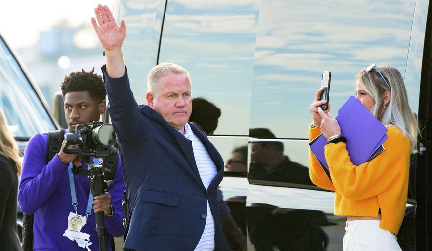 New LSU football coach Brian Kelly gestures to fans after his arrival at Baton Rouge Metropolitan Airport, Tuesday, Nov. 30, 2021, in Baton Rouge, La. Kelly, formerly of Notre Dame, is said to have agreed to a 10-year contract with LSU worth $95 million plus incentives.  (AP Photo/Matthew Hinton)
