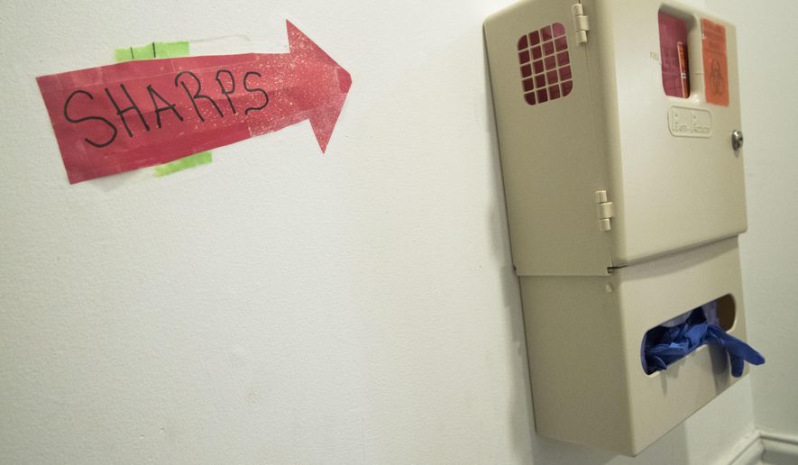 In this June 19, 2018, photo, a safe needle disposal container hangs in the bathroom of VOCAL-NY headquarters in the Brooklyn borough of New York. The first officially authorized safe havens for people to use heroin and other narcotics have been cleared to open in New York City in hopes of curbing overdoses, the mayor and health commissioner said Tuesday, Nov. 30, 2021. (AP Photo/Mary Altaffer)