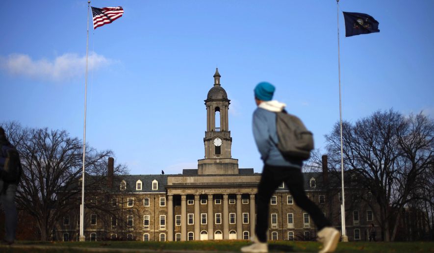 In this Friday, Nov. 11, 2011, file photo, a student walks in front of the Old Main building on the Penn State campus in State College, Pa.  (AP Photo/Matt Rourke, File)
