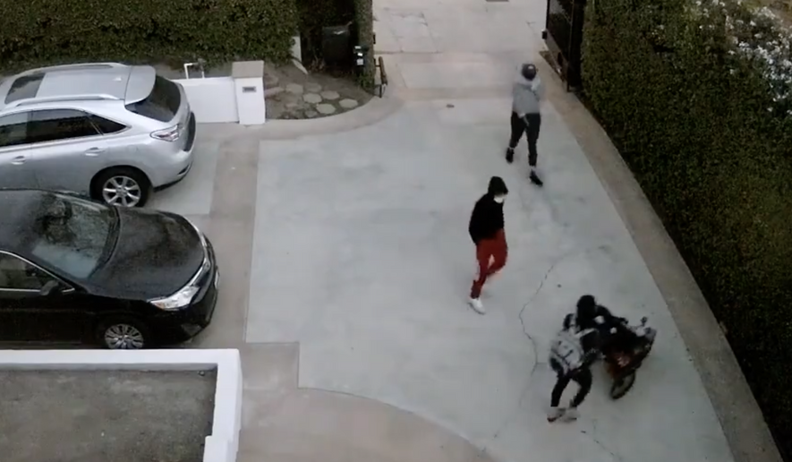 Surveillance video shows robbers targeting a mother with a baby in a stroller after she opened the gates to her home in Los Angeles, police said. (screengrab via Los Angeles Police Department video)