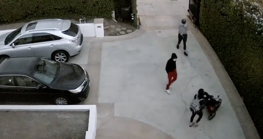 Surveillance video shows robbers targeting a mother with a baby in a stroller after she opened the gates to her home in Los Angeles, police said. (screengrab via Los Angeles Police Department video)