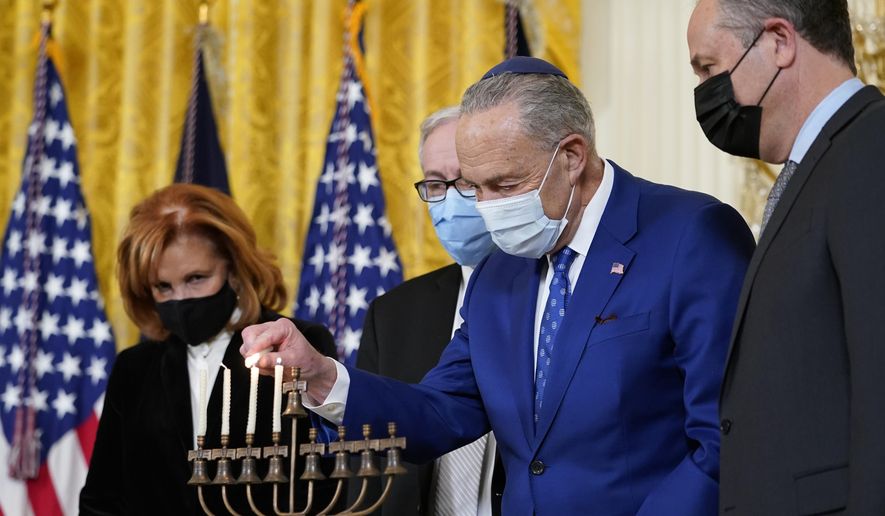 Senate Majority Leader Chuck Schumer of N.Y., second from right, lights the menorah in the East Room of the White House in Washington, during an event to celebrate Hanukkah, Wednesday, Dec. 1, 2021. Others watching are, from left, Jewish community leader Susan Stern, Dr. Rabbi Aaron Glatt, and second gentleman Doug Emhoff. (AP Photo/Susan Walsh)