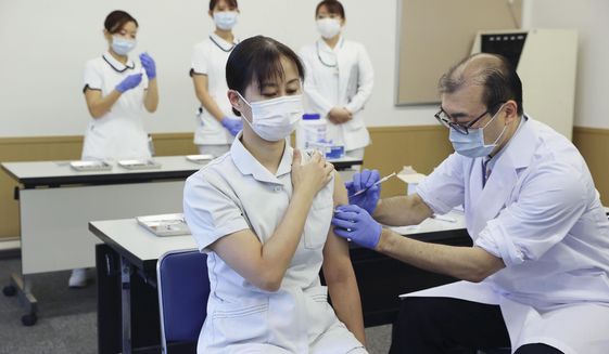 A medical worker of Tokyo Medical Center receives a booster shot of the Pfizer COVID-19 vaccine Wednesday, Dec. 1, 2021, in Tokyo. Japan has started administering the booster shots to health care workers on Wednesday. (Kyodo News via AP)
