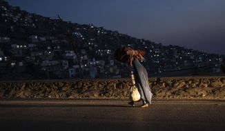 An Afghan women wearing a burka, carries a carpet as she walks in Kabul, Afghanistan, on Thursday, Dec, 2, 2021. (AP Photo/Petros Giannakouris)