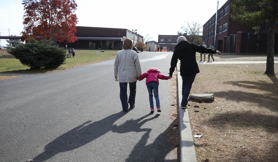 An Afghan refugee family walks past temporary housing in Liberty Village on Joint Base McGuire-Dix- Lakehurst in Trenton, N.J., Thursday, Dec. 2, 2021. (Barbara Davidson/Pool via AP) **FILE**