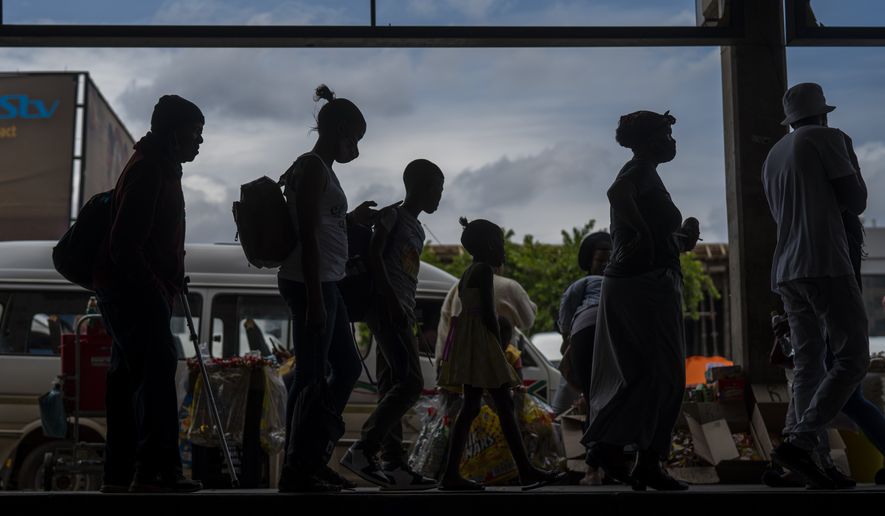 Passengers, some wearing masks, line up to board a taxi at the Baragwanath taxi rank in Soweto, South Africa, Thursday Dec. 2, 2021. South Africa launched an accelerated vaccination campaign to combat a dramatic rise in confirmed cases of COVID-19 a week after the omicron variant was detected in the country. (AP Photo/Jerome Delay)